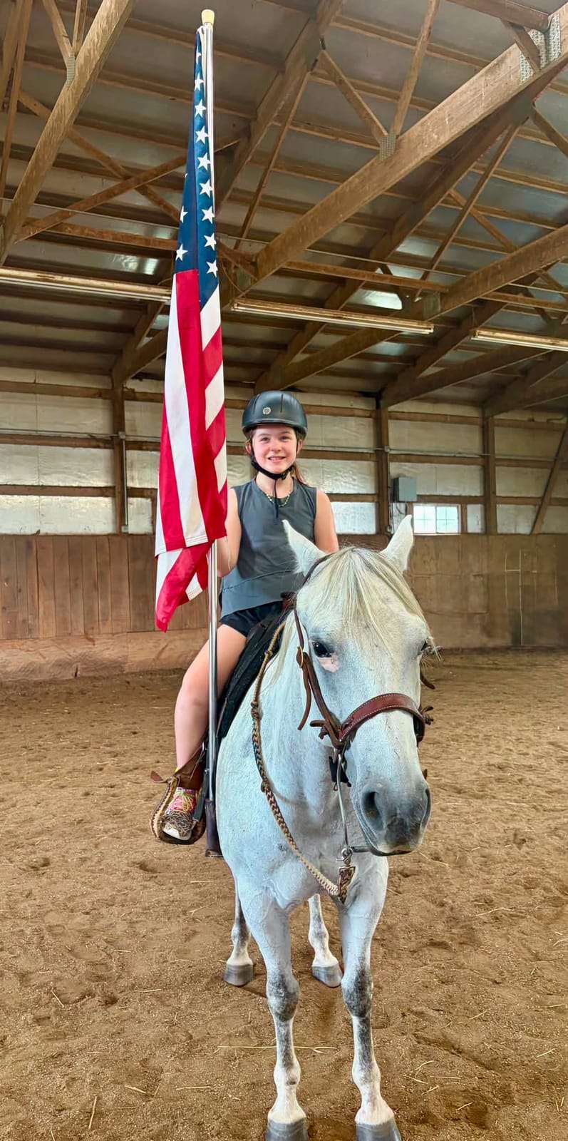 Camper on a grey horse beside the American flag