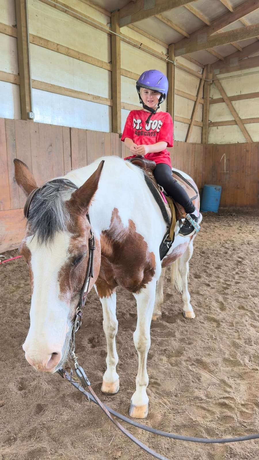 Camper riding a paint horse in the arena
