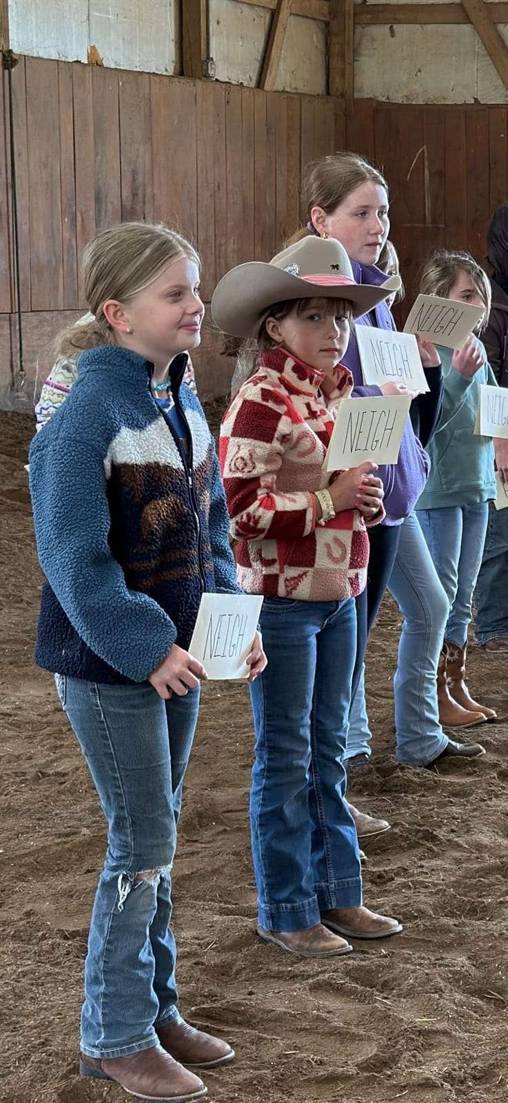 Campers holding Night Sun Stables activity cards in the arena