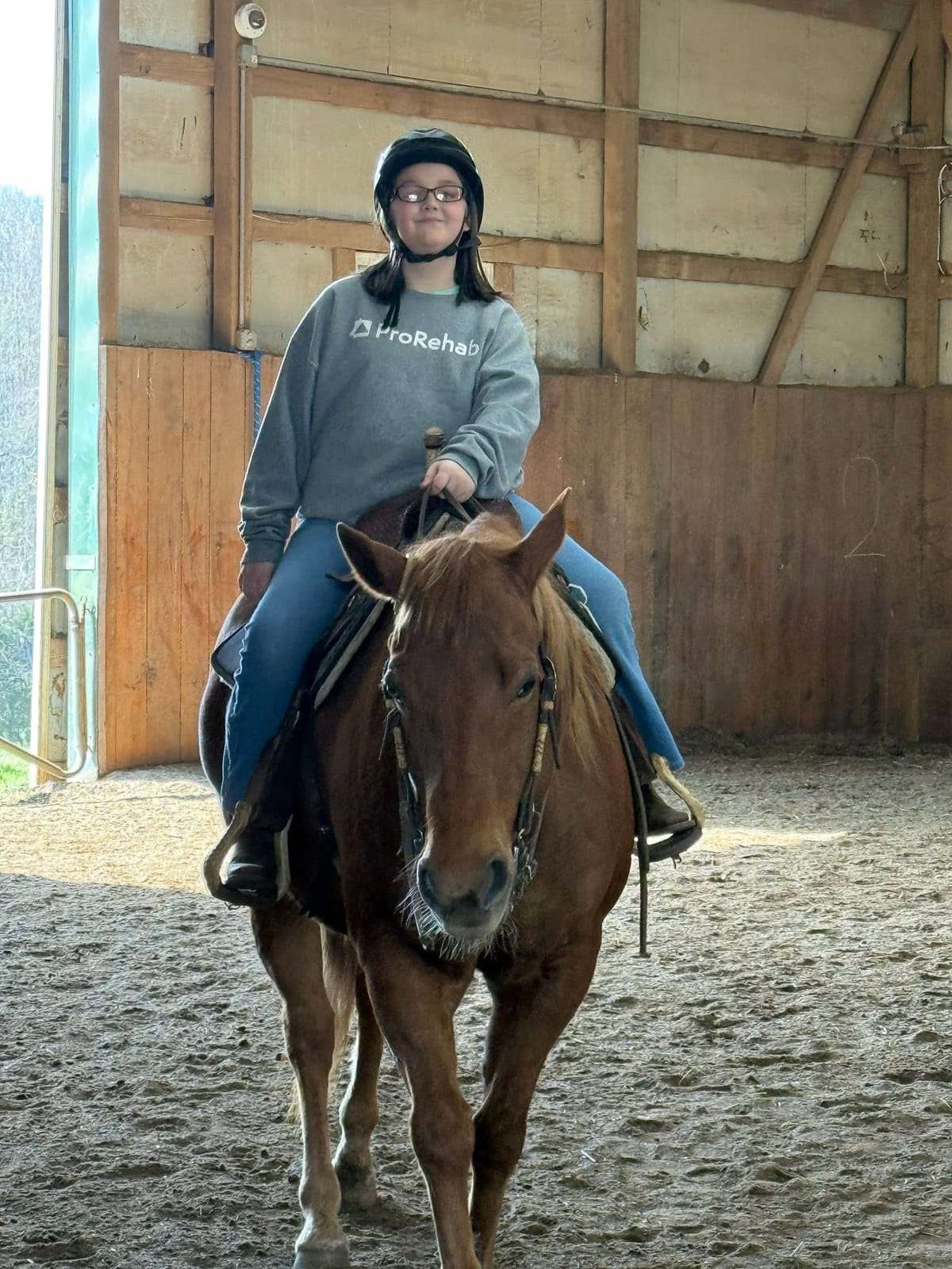 Camper riding a chestnut horse in the arena