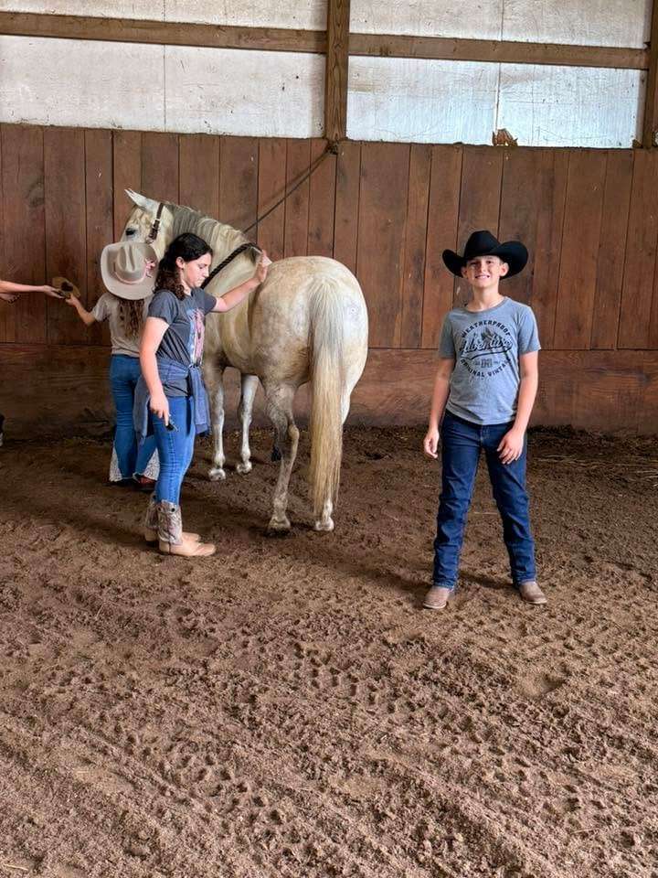 A camper and counselor leading a palomino horse