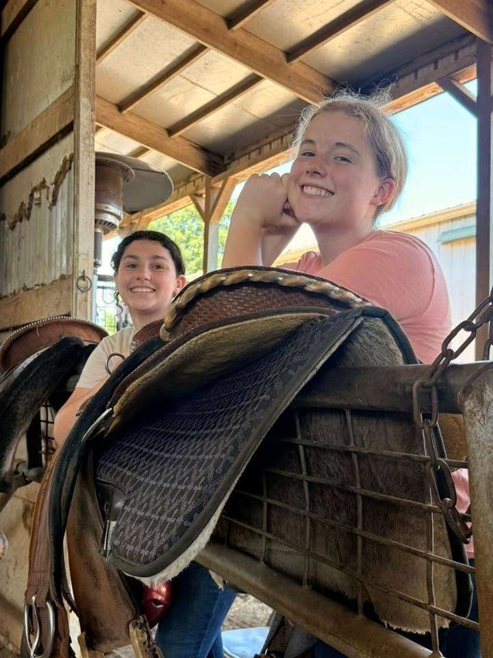 Counselors carrying a western saddle to tack up a horse