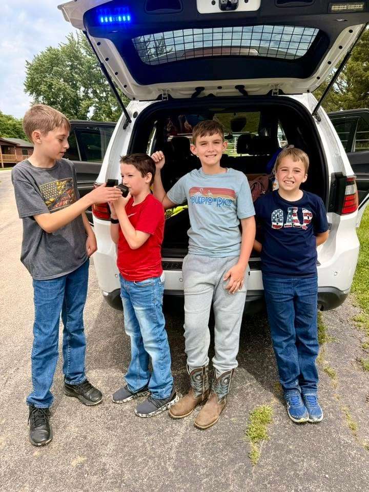 Campers meeting a sheriff's deputy and patrol vehicle at camp