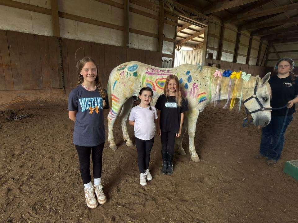 Campers with a rainbow-painted horse at summer camp
