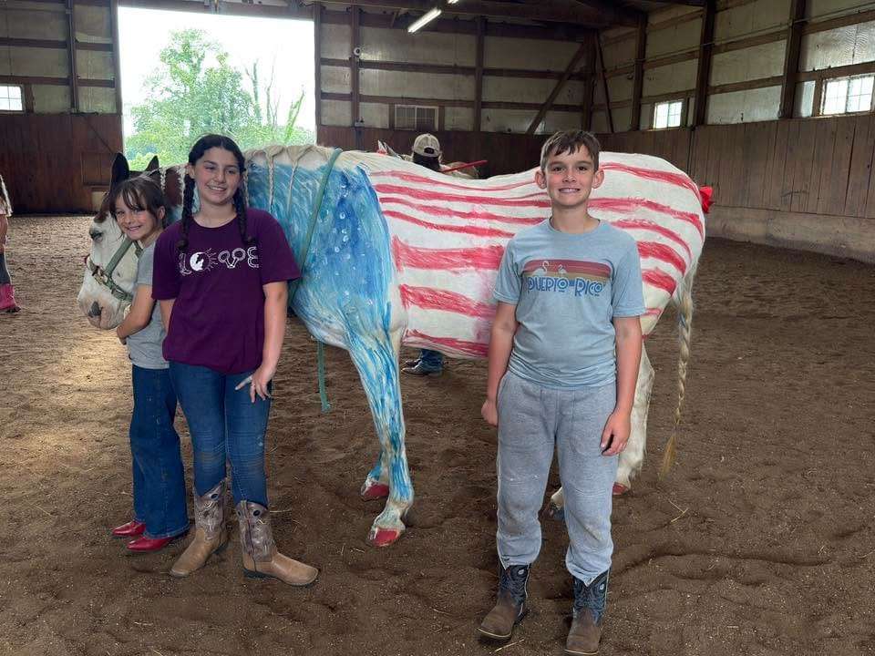 Campers posing with a patriotic flag-painted horse