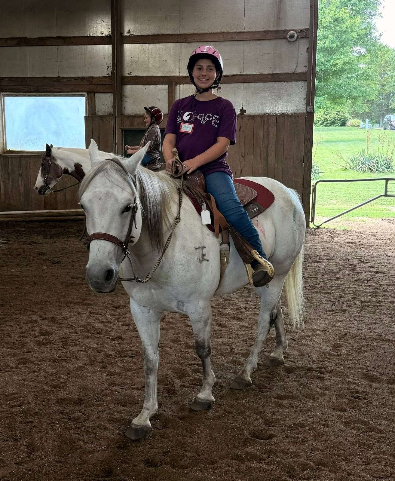 Camper riding a grey horse during camp