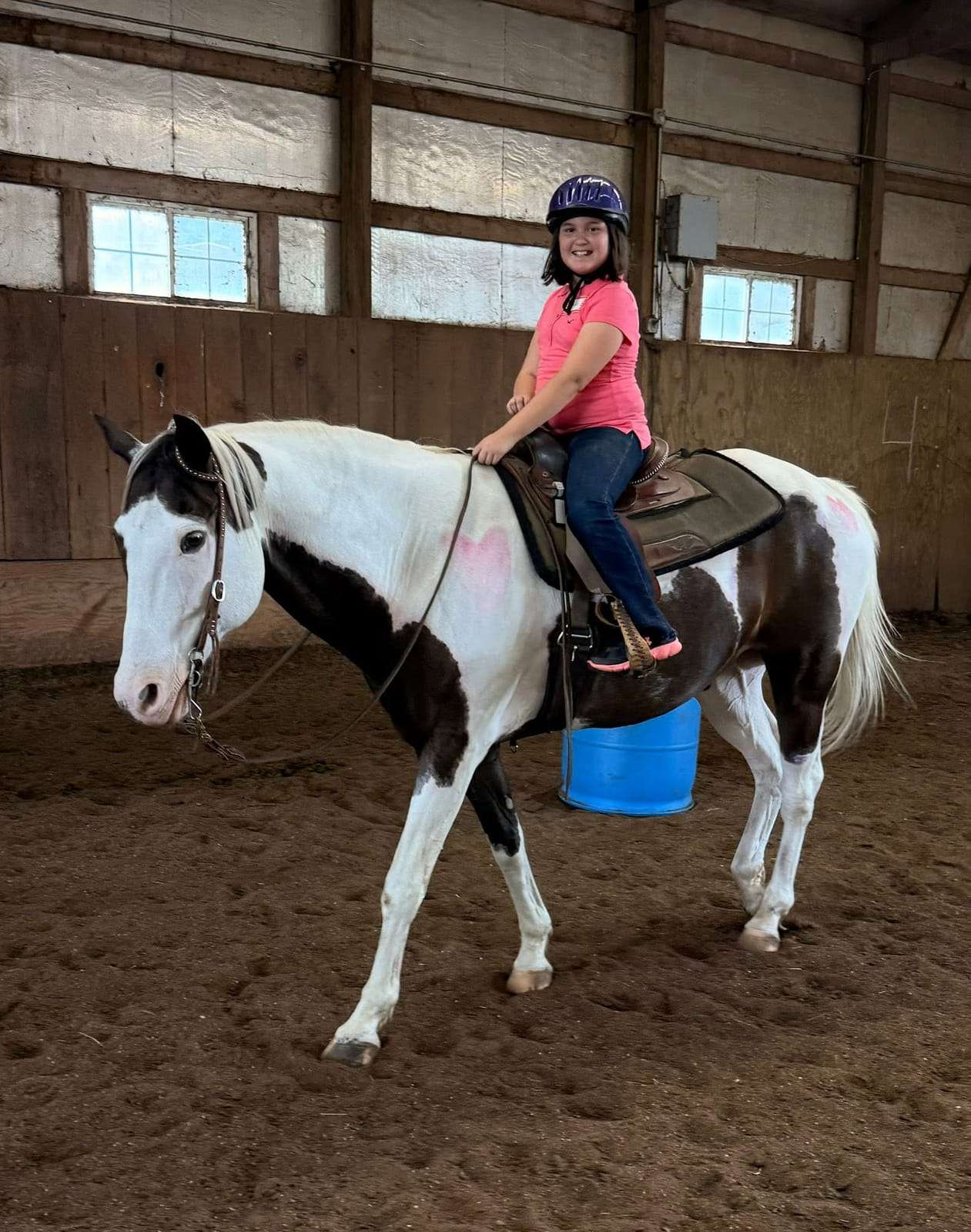 Young camper riding a paint horse in the arena