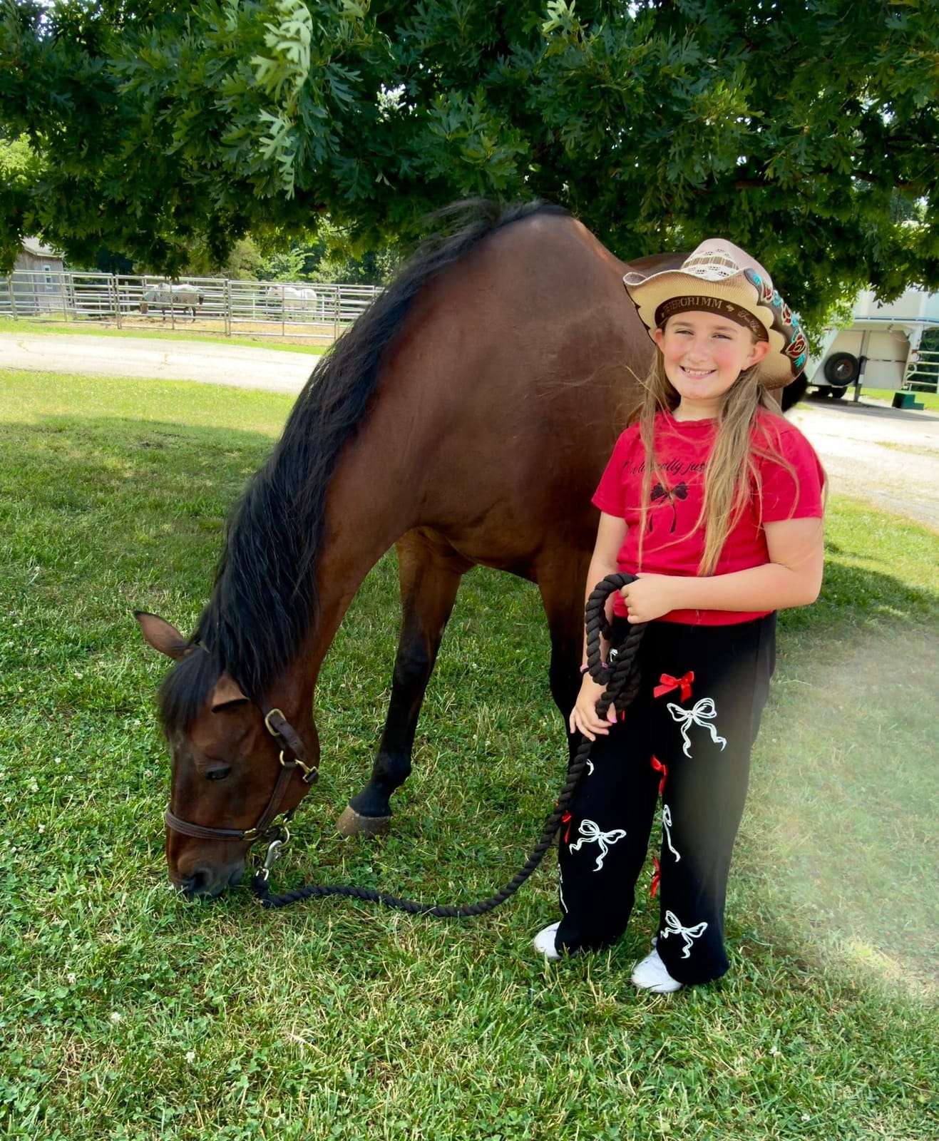 Camper with a bay horse grazing on the grass